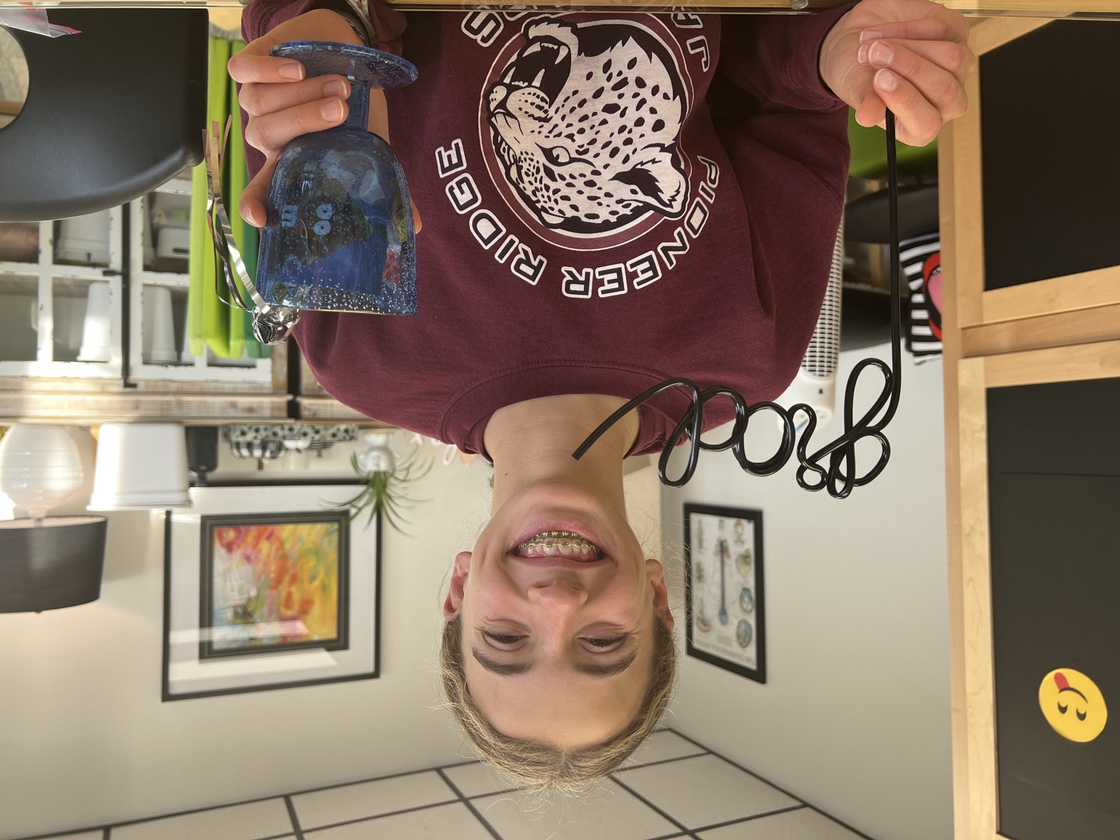A smiling teen holding a graduation straw and a decorated cup to celebrate finishing therapy